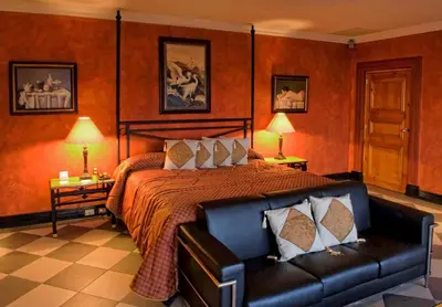 a bedroom with a bed and a leather couch at Hotel Villa Caletas in Jacó