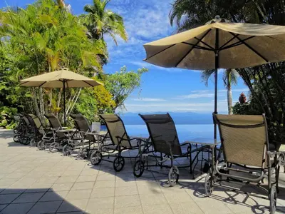 a group of chairs and tables with an umbrella at Hotel Villa Caletas in Jacó