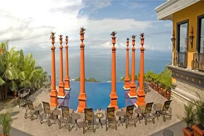 a patio with chairs and a view of the ocean at Hotel Villa Caletas in Jacó