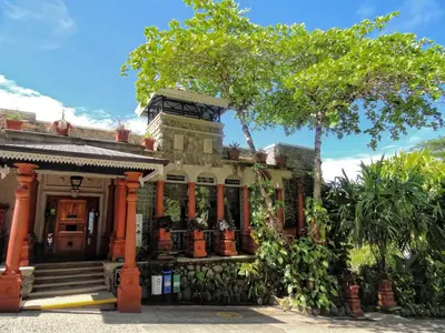 an old house with a tree in front of it at Hotel Villa Caletas in Jacó