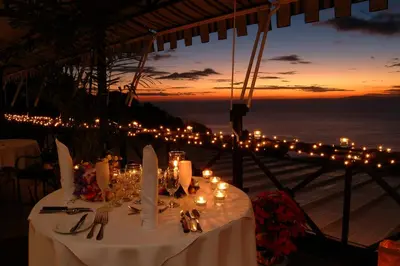 a table with candles and plates and utensils and lights at Hotel Villa Caletas in Jacó