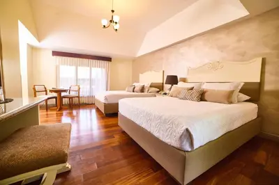 a large bedroom with two beds and a table at El Rodeo Estancia Boutique Hotel & Steakhouse in San José