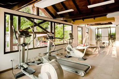 a gym with cardio equipment in a room with windows at El Rodeo Estancia Boutique Hotel & Steakhouse in San José