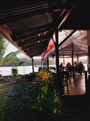 a group of people sitting at a table on the beach at Chinitas Eco Lodge in Tortuguero