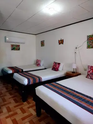 two beds in a room with white walls at Chinitas Eco Lodge in Tortuguero