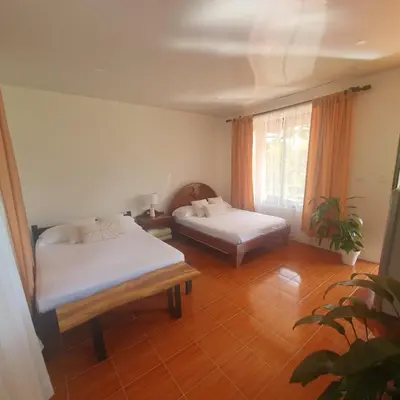 a room with two beds and a window at Lumbres Arenal in Fortuna
