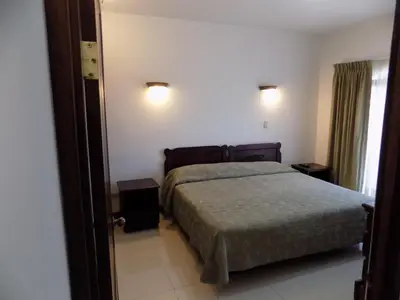a bedroom with a bed and two lights on the wall at Hotel Plaza Real Suites & Apartments San Jose in San José