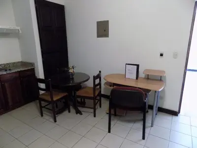 a room with two tables and chairs and a kitchen at Hotel Plaza Real Suites & Apartments San Jose in San José