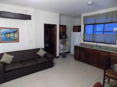 a living room with a couch and a large window at Hotel Plaza Real Suites & Apartments San Jose in San José
