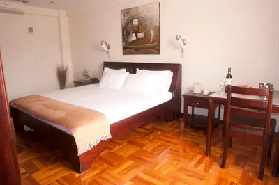 a bedroom with a bed and a table with a chair at Hotel Plaza Real Suites & Apartments San Jose in San José