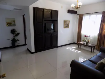 a living room with a couch and a tv at Hotel Plaza Real Suites & Apartments San Jose in San José
