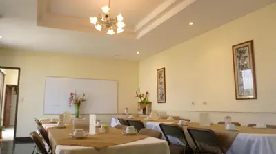 a conference room with tables and chairs and a whiteboard at Hotel Plaza Real Suites & Apartments San Jose in San José