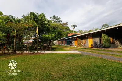 a house with a grass yard next to a building at Rio Celeste Dreams in Bijagua