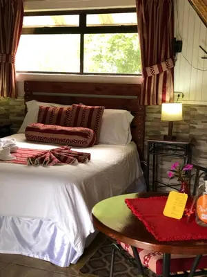 a bedroom with a bed and a table and a window at Hortensias Chalets Vara blanca in Heredia