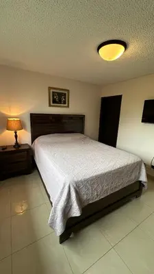 a bedroom with a large bed and a lamp at Jaco Beach Penthouse in Jacó