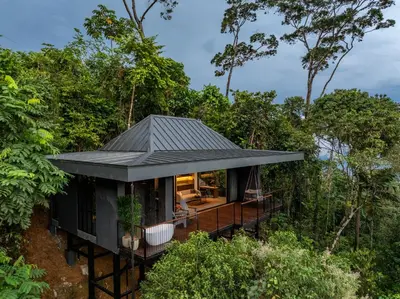 a house in the forest with a black roof at Rancho Pacifico - Boutique Hotel for Adults in Uvita
