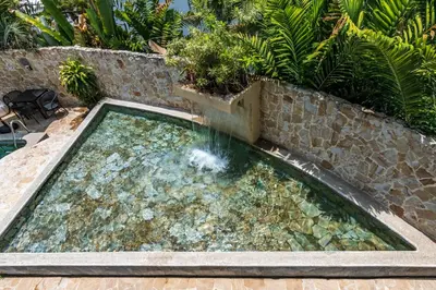 a pool with a waterfall in a garden at Gaia Hotel & Reserve- Adults Only in Manuel Antonio