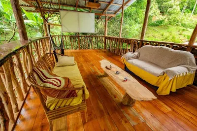a porch with a couch and a chair on a wooden floor at Cascada Elysiana in Platanillo