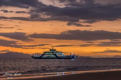a boat in the ocean with a sunset in the background at Ruiselares in Puntarenas