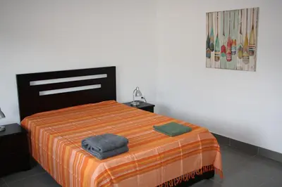 a bedroom with a bed with an orange and orange blanket at Apartamentos La Alborada Airport SJO in Alajuela City