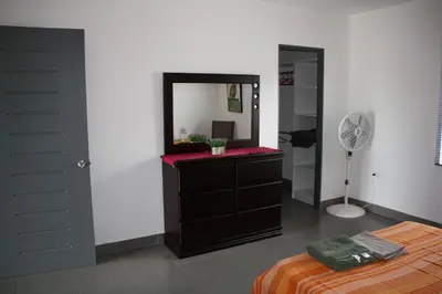 a bedroom with a dresser with a mirror and a fan at Apartamentos La Alborada Airport SJO in Alajuela City