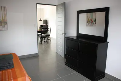 a living room with a black dresser with a mirror at Apartamentos La Alborada Airport SJO in Alajuela City