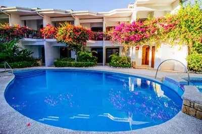 a swimming pool in front of a building with flowers at Hotel Giada in Sámara