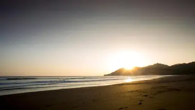 a beach with the sun setting in the distance at Hotel Giada in Sámara