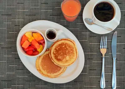 a plate with pancakes and fruit and a cup of coffee at Hotel Giada in Sámara