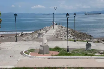 a statue on a sidewalk next to the ocean at Hotel Yadran Beach Resort in Puntarenas