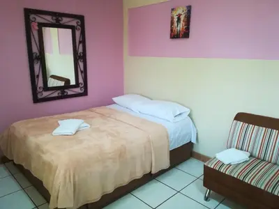a bedroom with two beds and a mirror and a chair at Belis in Alajuela City