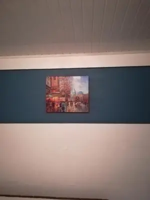 a painting is hanging on a blue wall at Belis in Alajuela City