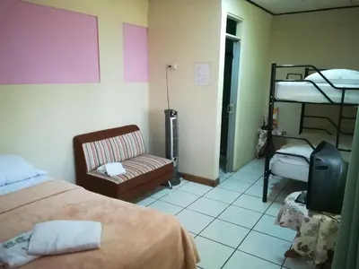 a room with a bed and a chair and bunk beds at Belis in Alajuela City