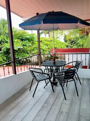 a table and chairs with an umbrella on a balcony at Villa Guarias in Puntarenas