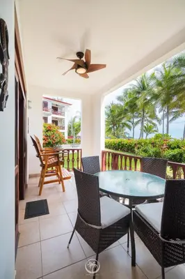 a balcony with a table and chairs and palm trees at Bahia Azul 2A beachfront, Jaco Beach, 1st floor in Jacó