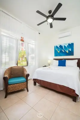 a bedroom with a bed and a chair and a ceiling fan at Bahia Azul 2A beachfront, Jaco Beach, 1st floor in Jacó