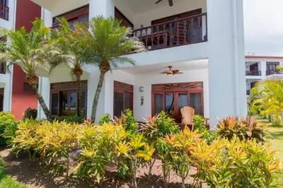 a house with palm trees in front of it at Bahia Azul 2A beachfront, Jaco Beach, 1st floor in Jacó