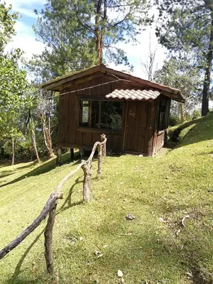 a small wooden cabin with a fence in the grass at Cabañas Don Camilo Albergue de Montaña in Cabecera de Cañas