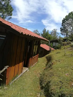 a building with a red roof on top of a field at Cabañas Don Camilo Albergue de Montaña in Cabecera de Cañas