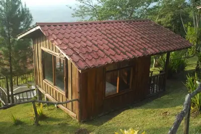 a small cabin with a red roof on the grass at Cabañas Don Camilo Albergue de Montaña in Cabecera de Cañas