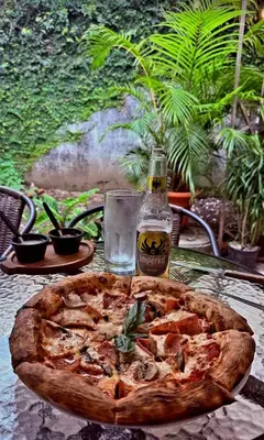 a pizza sitting on a table with a bottle of beer at Nature house in Monteverde Costa Rica