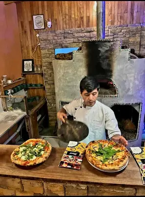 a man preparing two pizzas on a table at Nature house in Monteverde Costa Rica