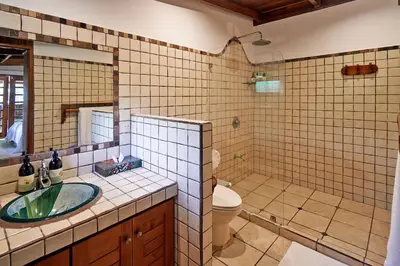 a bathroom with a sink and a toilet and a mirror at Hotel Tropico Latino in Santa Teresa Beach