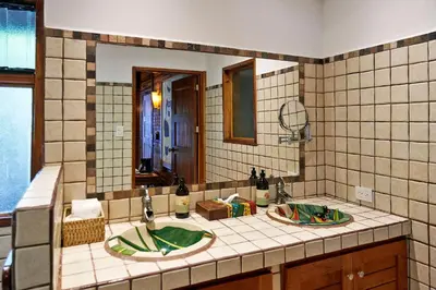 a bathroom with two sinks and a mirror at Hotel Tropico Latino in Santa Teresa Beach
