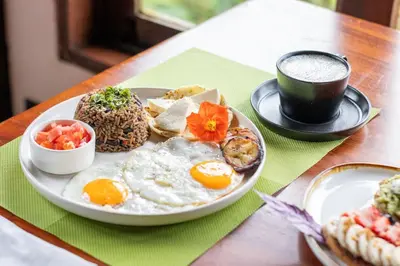 a plate of breakfast food with eggs and a cup of coffee at Villa Blanca Cloud Forest Hotel & Retreat in San Ramón