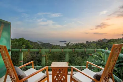 a balcony with chairs and a table and a view of the ocean at Si Como No Resort & Wildlife Refuge in Manuel Antonio