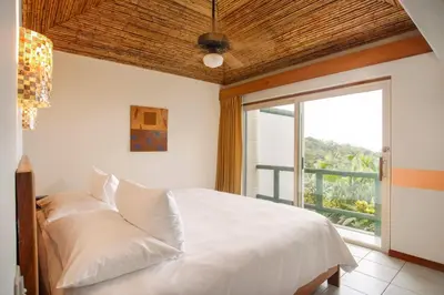 a bedroom with a white bed with a large window at Si Como No Resort & Wildlife Refuge in Manuel Antonio