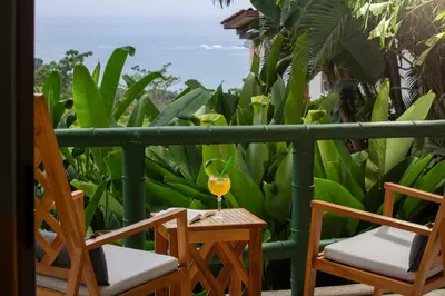 a glass of juice sitting on a table on a balcony at Si Como No Resort & Wildlife Refuge in Manuel Antonio