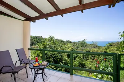 a balcony with a table and chairs and the ocean at Si Como No Resort & Wildlife Refuge in Manuel Antonio