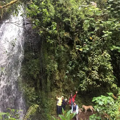 a group of people standing in front of a waterfall at Cabaña de montaña La Magnolia, Cerro de la Muerte De La Cañuela Cloud Forest in Tres de Junio